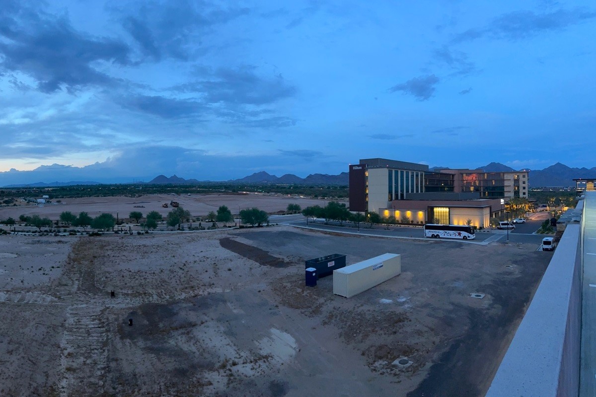 Evening view of Hilton hotel in Cavasson, Scottsdale, Arizona, with desert landscape and mountains in the distance under a twilight sky.