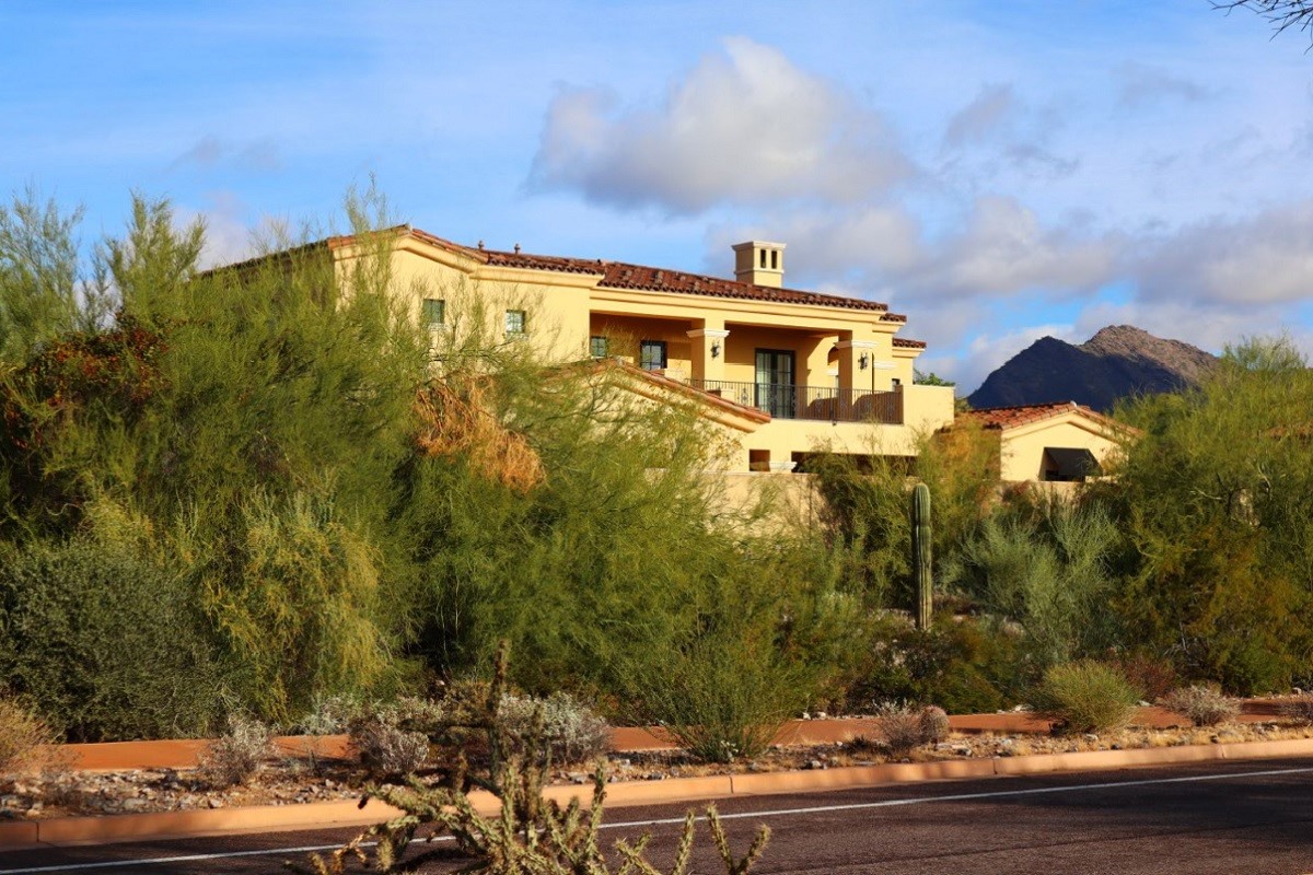 Mediterranean-style Scottsdale home surrounded by desert plants with mountains in the background.