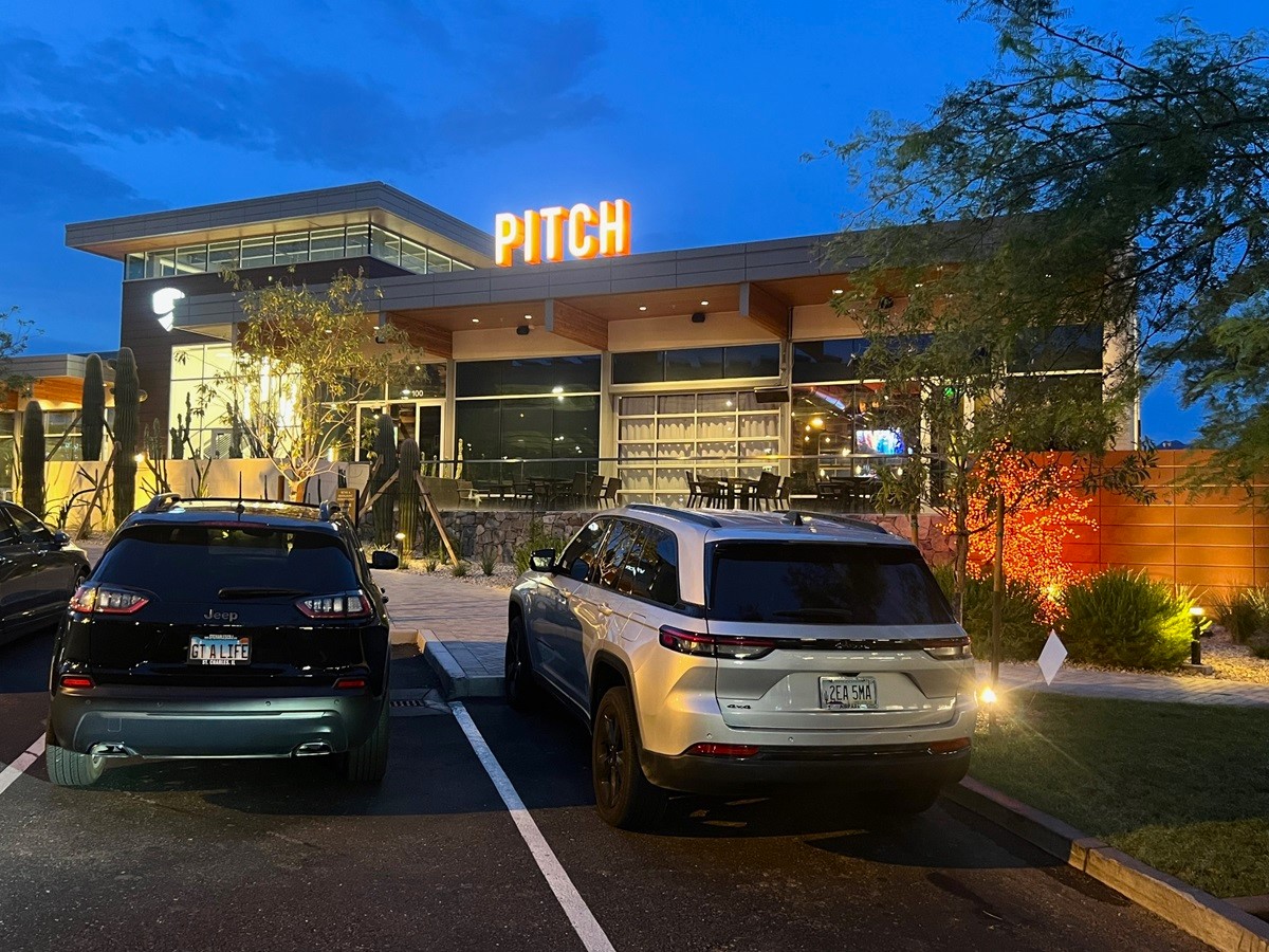Pitch restaurant in Scottsdale at night, with modern architecture and cars parked in front. 