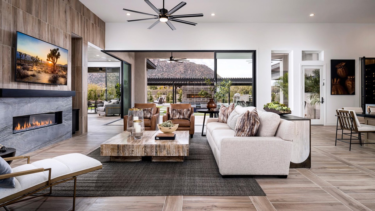 Spacious living room with sliding doors opening to an outdoor patio, featuring a modern fireplace, wood accents, and stunning mountain views.