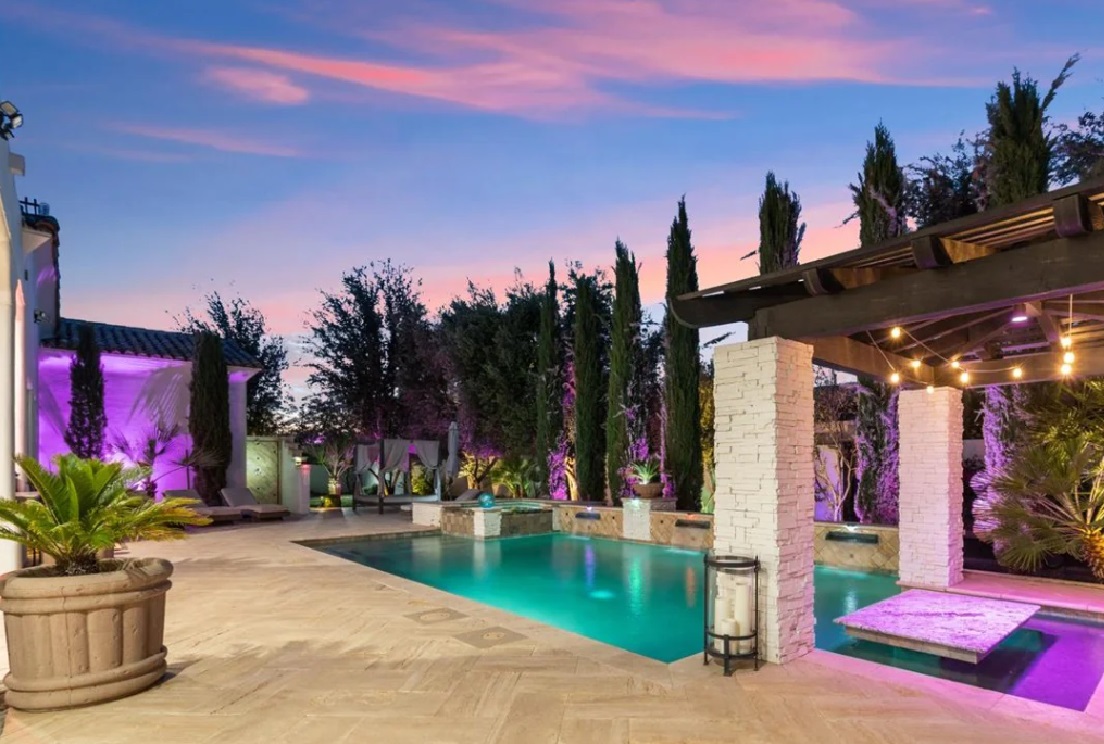 Luxury backyard with a modern pool, smart lighting, and cozy cabana, showcasing elegant outdoor ambiance at sunset.
