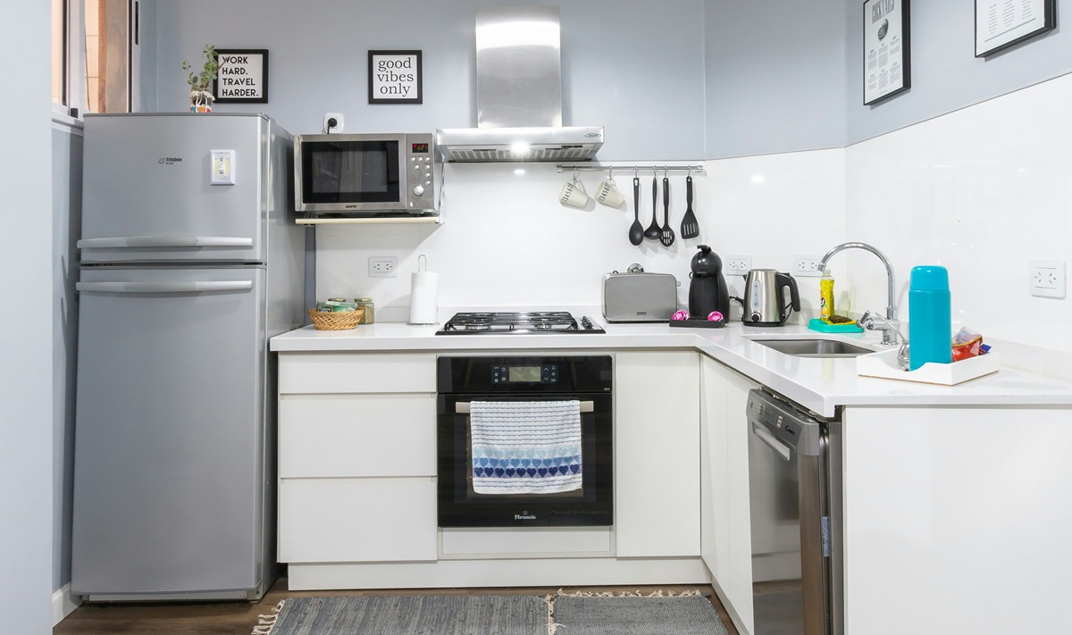 Compact kitchen with white cabinets, stainless appliances, and minimal decor.