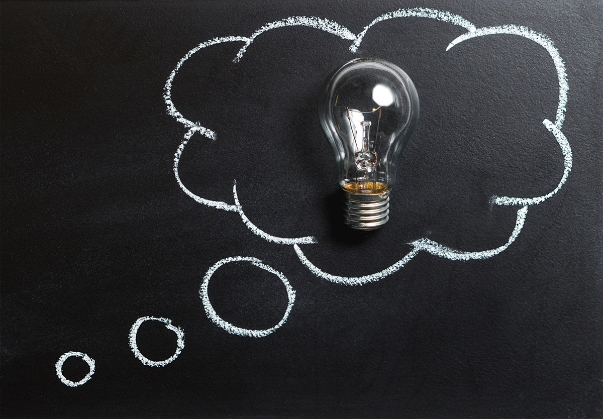 A glowing light bulb on a chalkboard, surrounded by a thought bubble drawn in chalk, symbolizing a creative idea or insight.