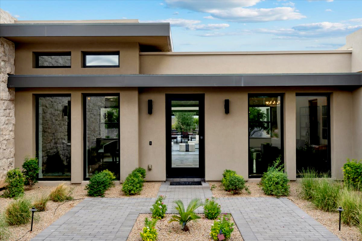 Modern luxury home entrance with sleek design and verdant landscaping.