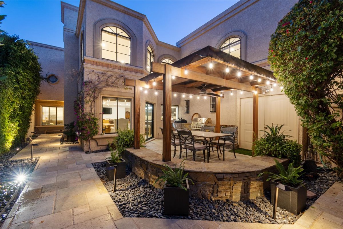 Backyard with a pergola, string lights, and outdoor dining area.