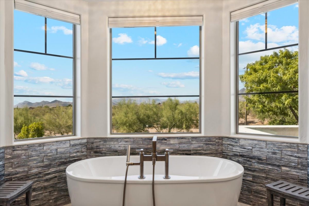 Luxurious bathroom with freestanding tub, large windows, and scenic desert views.