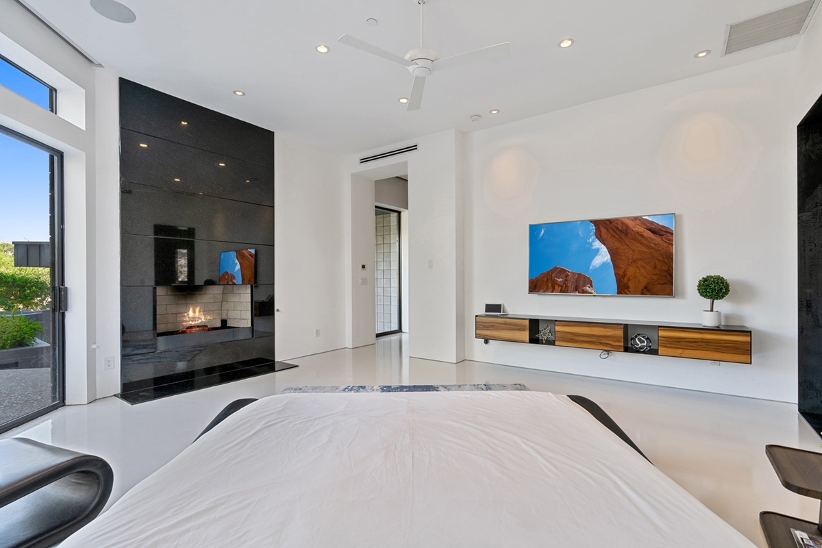 Contemporary bedroom with fireplace and mounted tv display.