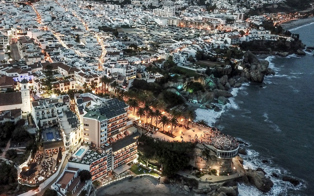 A vibrant coastal town in Nerja, Spain, lit up at night with charming streets and ocean views.