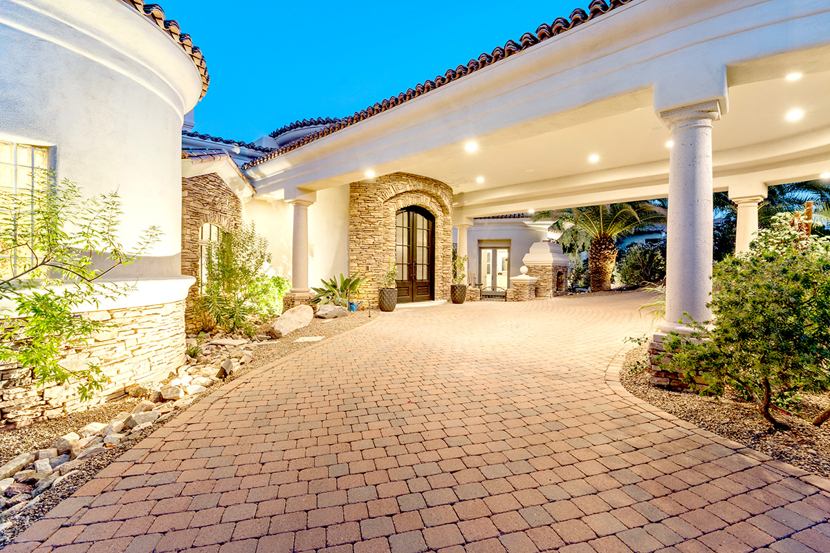 A luxurious estate In Artizona's Paradise Valley featuring a circular driveway and well-lit exterior design at dusk.