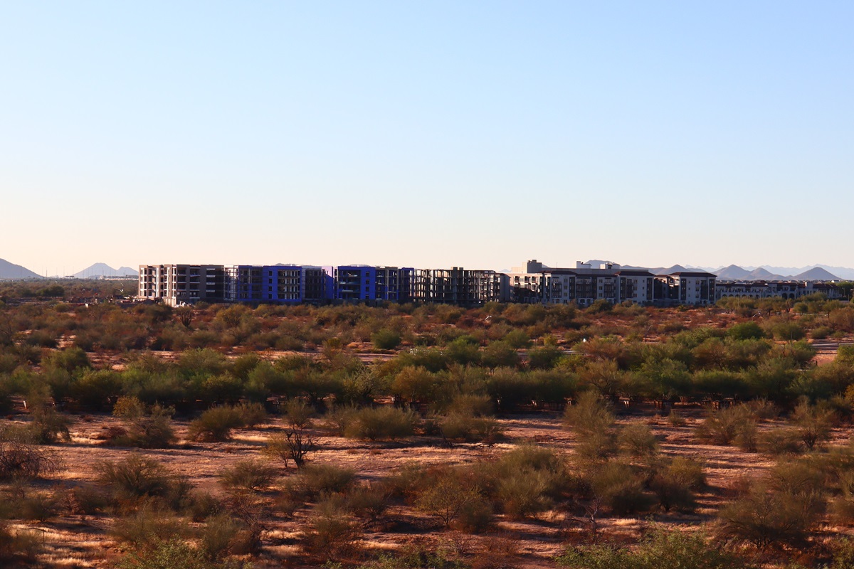 Portico Luxury Condos under construction, surrounded by desert landscape and mountain views.