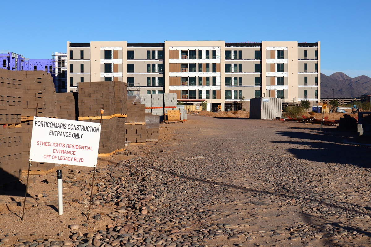Construction site at Portico with building materials and signage indicating ongoing development.