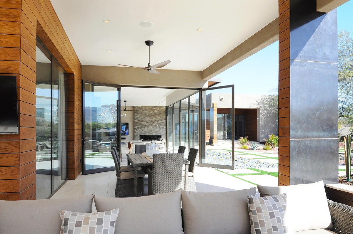 Scottsdale rental property featuring an outdoor dining area, cozy seating, and scenic views through floor-to-ceiling glass doors.