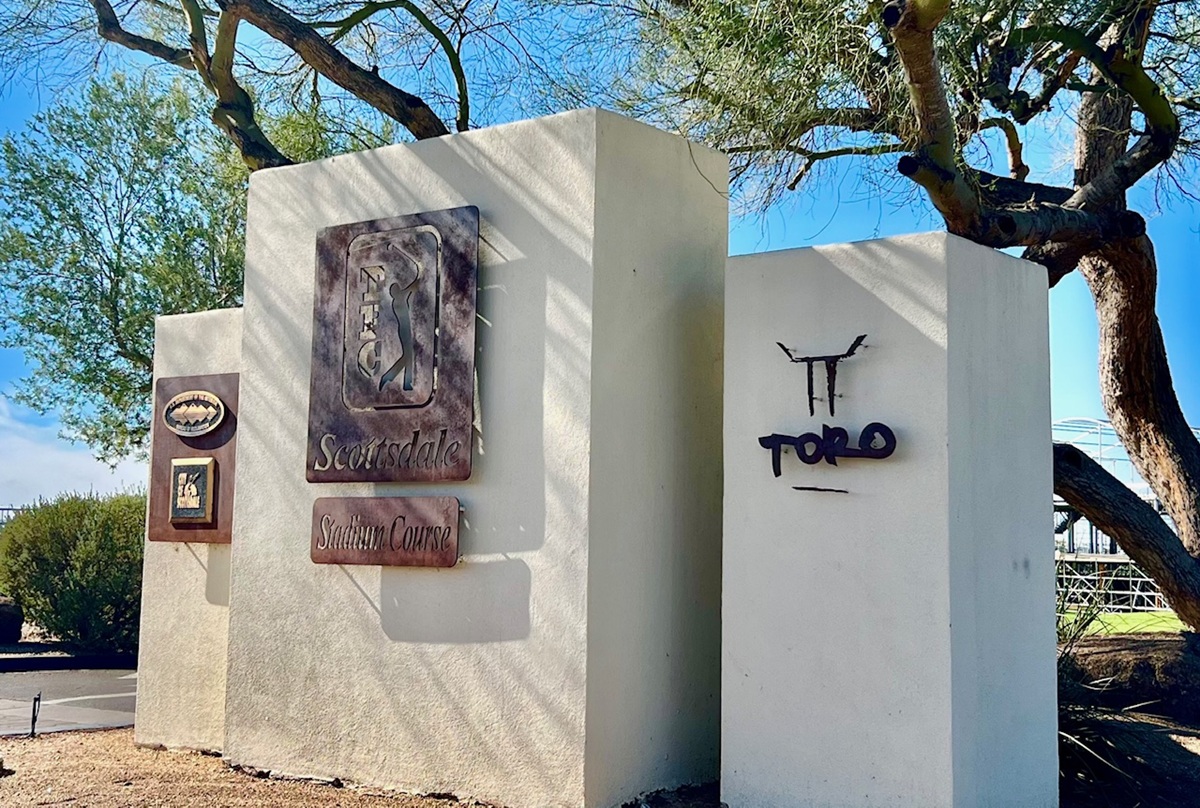 Entrance sign for TPC Scottsdale Stadium Course and Toro Restaurant, set against desert landscaping and blue skies.