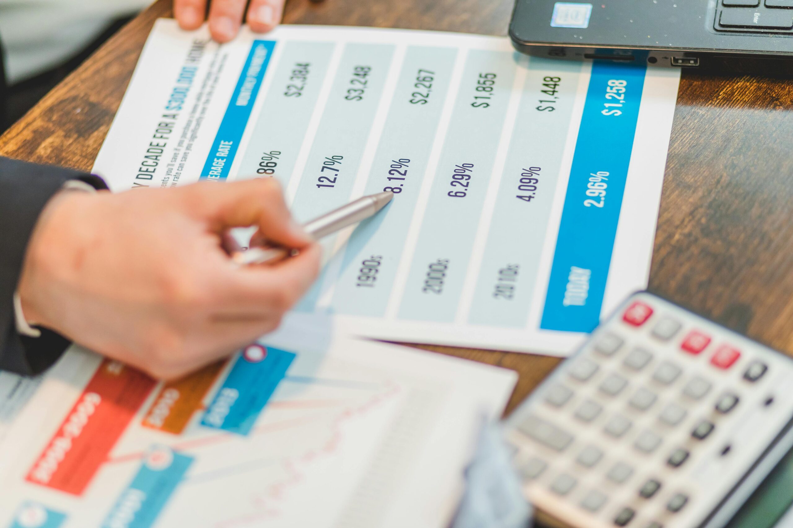 Hand pointing to a table of mortgage rates and monthly payments on printed documents.