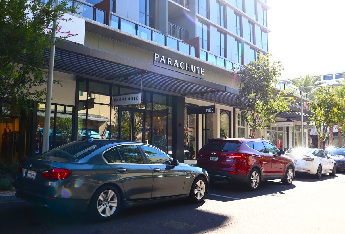 A trendy shopping street with high-end retail stores like "Parachute" and stylish storefronts, embodying Scottsdale's chic and sophisticated vibe.
