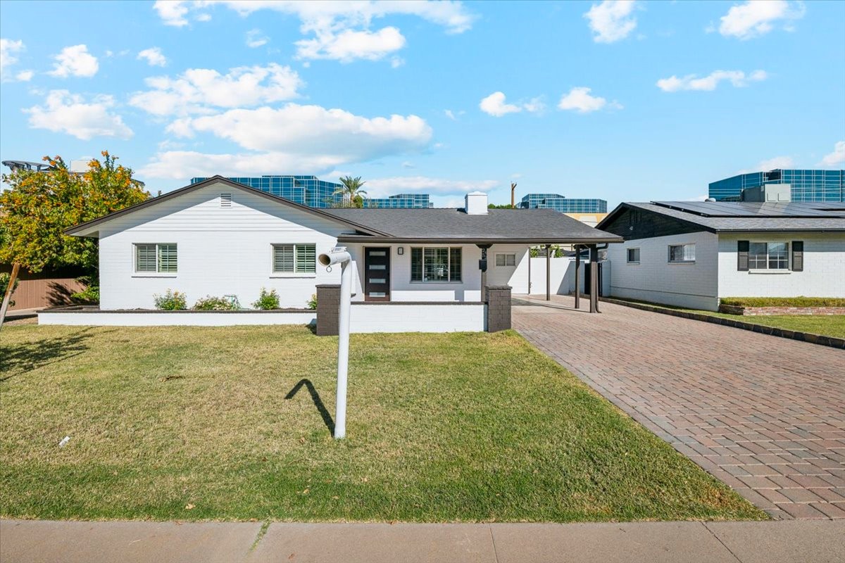 A single story home seen from the front as a blue sky with patchy clouds fill the sky.