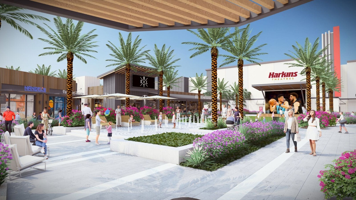 A conceptual rendering of a lively outdoor plaza in Verrado with palm trees, colorful landscaping, seating areas, and a Harkins Theatres building, creating a lively community space.