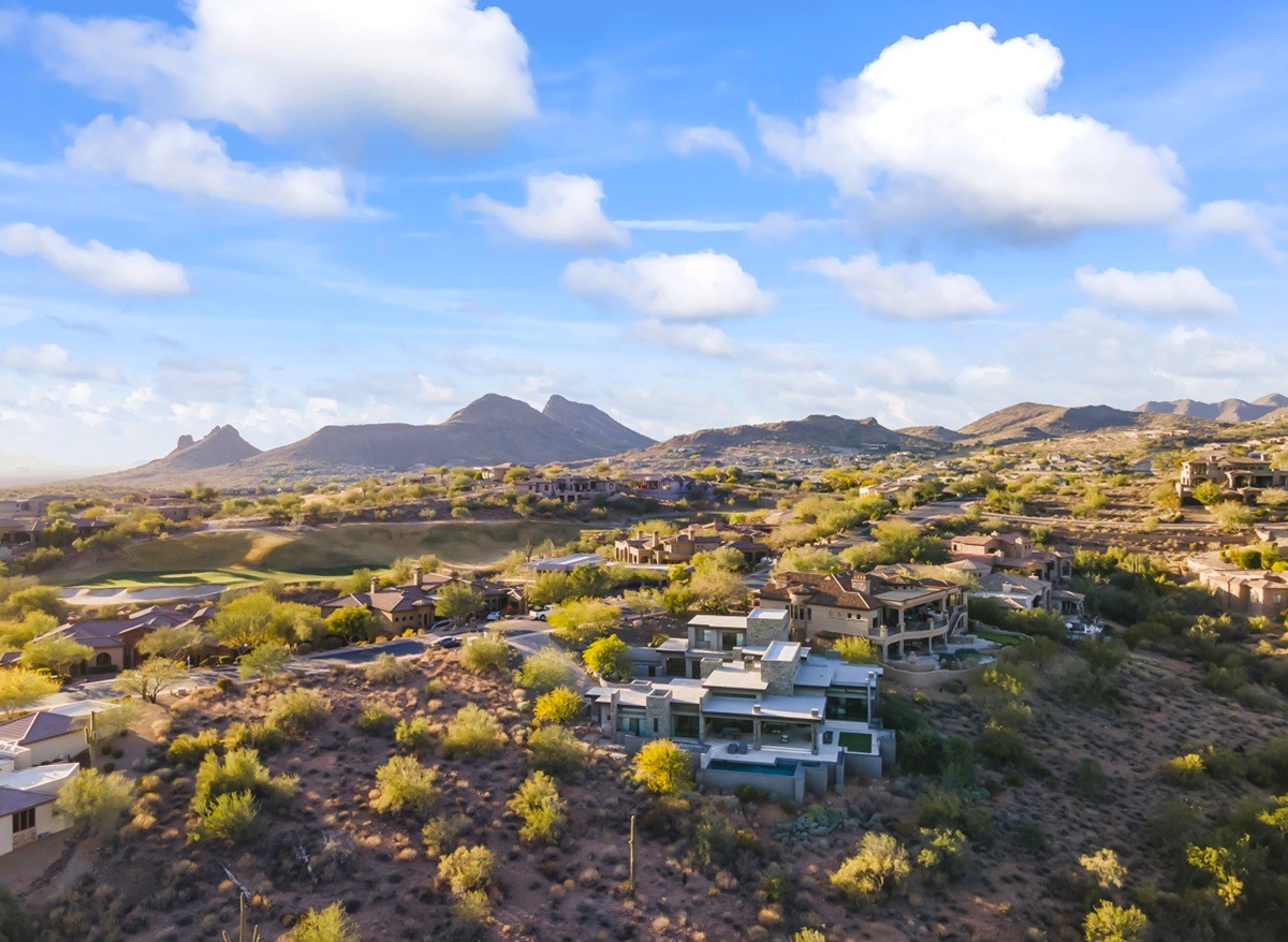 Scenic desert landscape with luxury homes nestled among rolling hills and mountain views.
