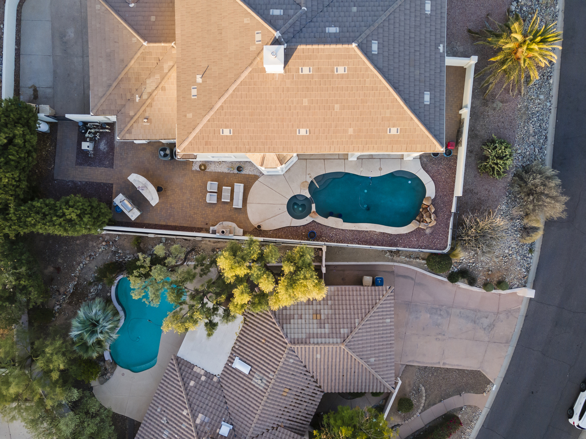 A top-down, angled drone shot of a luxury home with a pool and neighborhood in Fountain Hills.