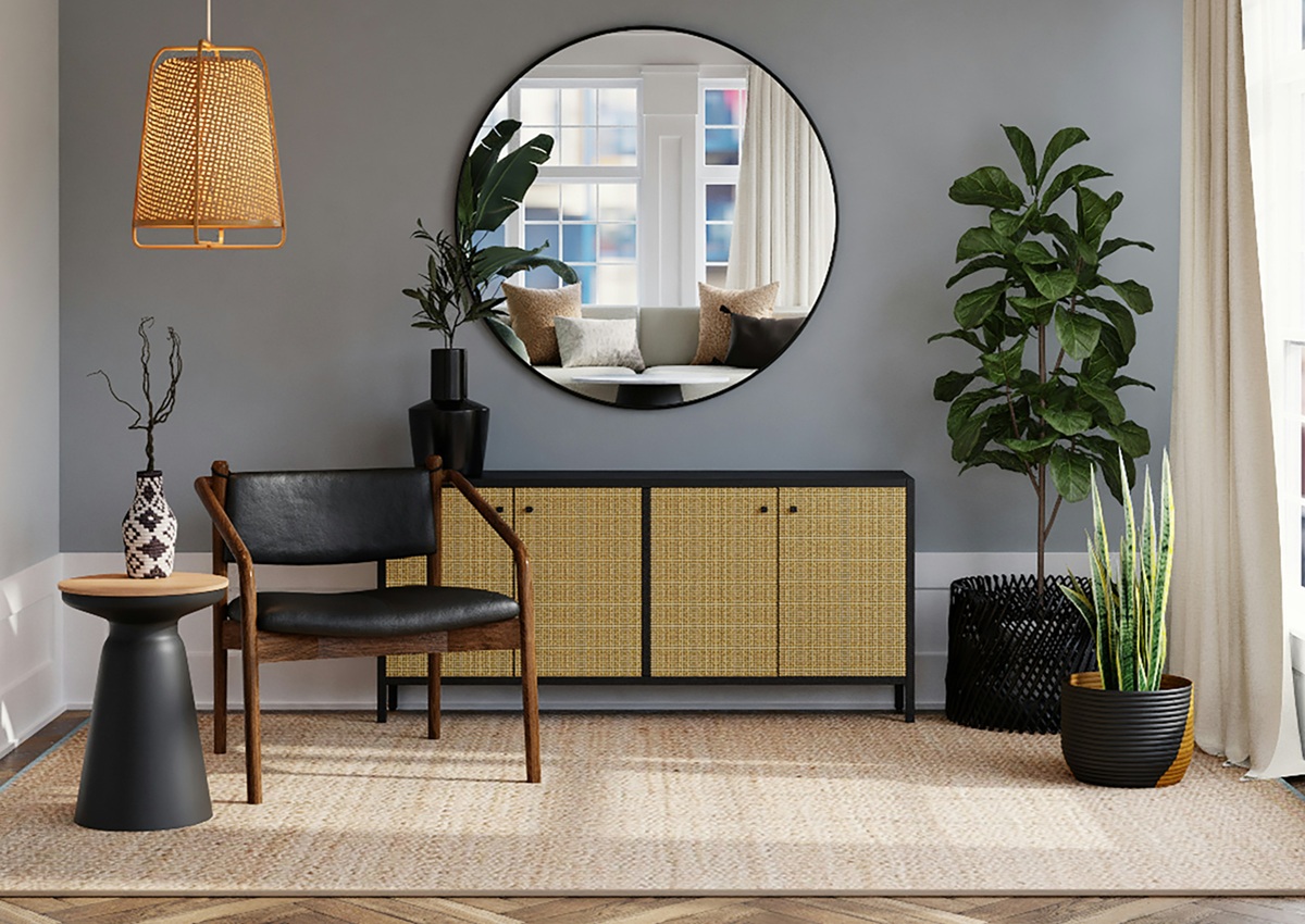 A modern living room corner with a round mirror, woven cabinet, black chair, potted plants, and a hanging rattan light fixture.