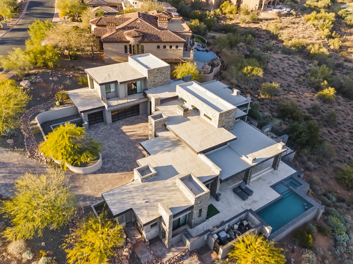Expansive aerial view of a contemporary luxury home in a desert setting.