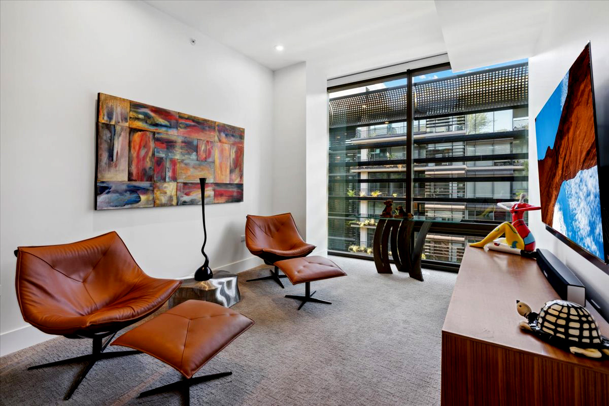 Modern interior design featuring leather chairs, colorful wall art, and large windows overlooking a contemporary building.