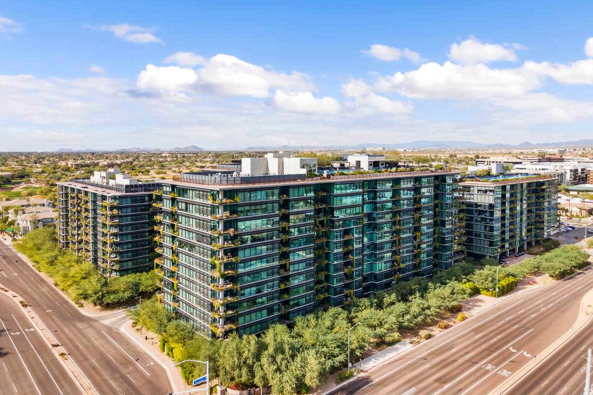 Modern mid-rise buildings with glass facades in Scottsdale, featuring green landscaping and clear views of surrounding suburban areas.