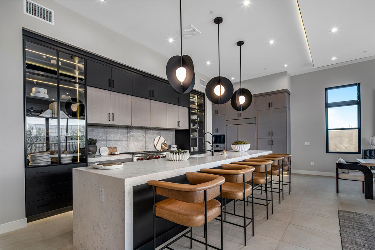 Modern kitchen with sleek black and wood cabinetry, a large marble island, and stylish pendant lighting.