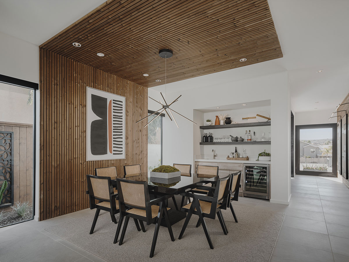 Chic dining area with wood-paneled walls, a built-in bar, and a statement light fixture.
