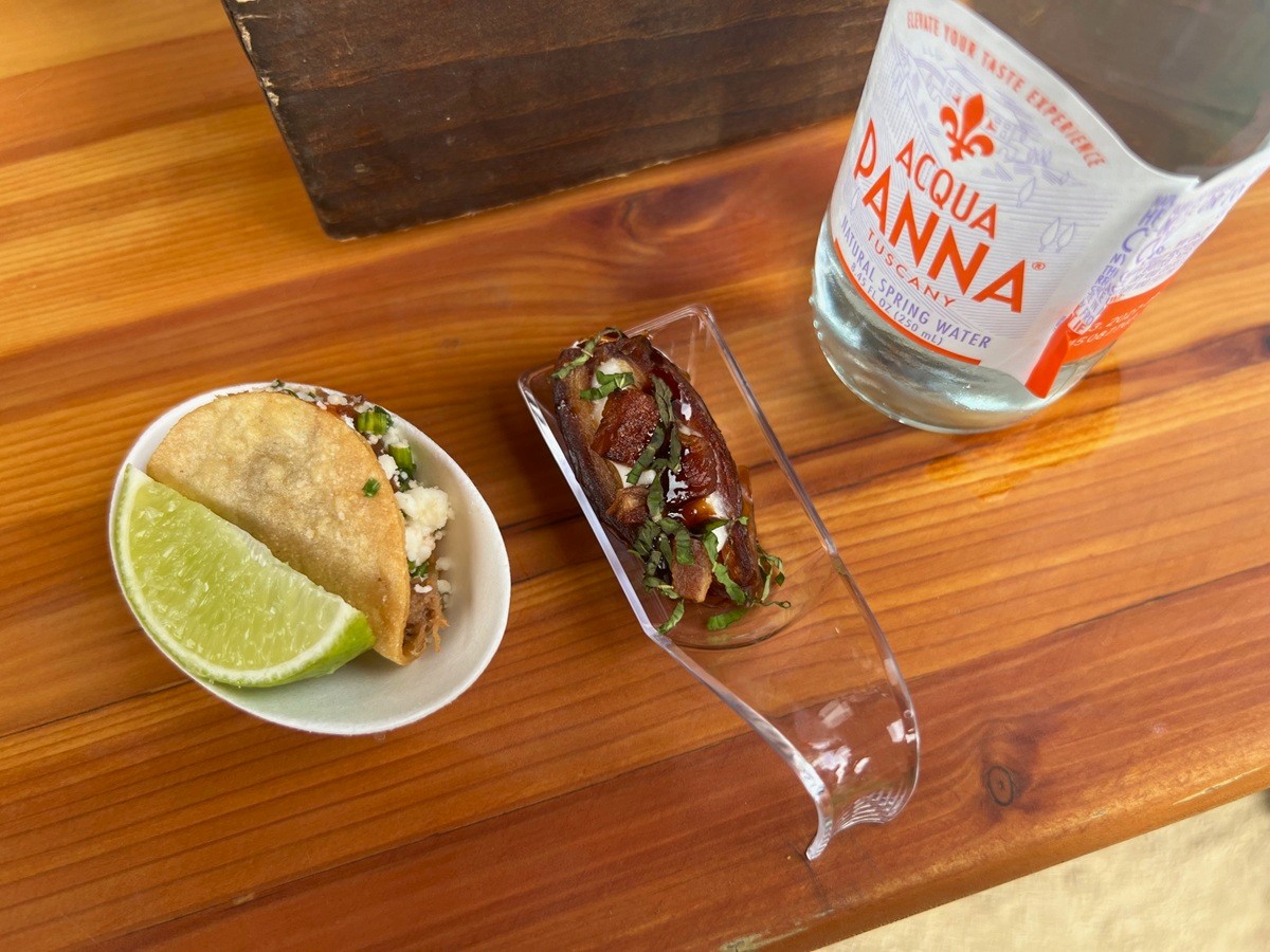 Close-up of elegant bite-sized appetizers and bottled water placed on a wooden table.