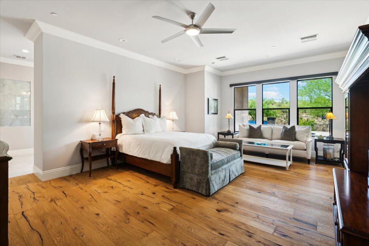 A spacious primary bedroom includes wood floors, large windows, and elegant furnishings.