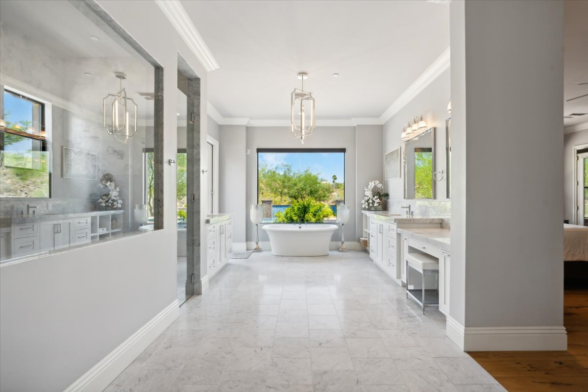 An elegant bathroom showcases a freestanding tub, dual vanities, and a large walk-in shower.