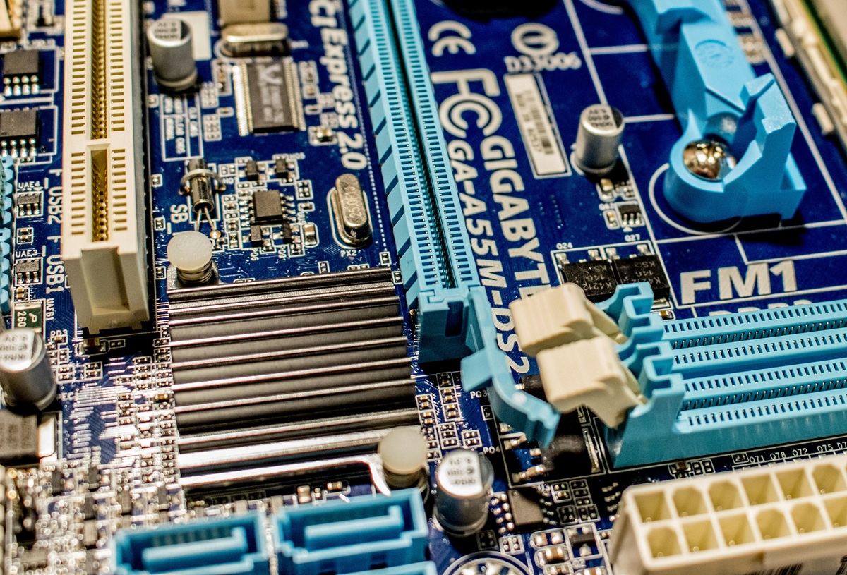 A detailed view of a blue motherboard with various slots, connectors, and electronic components, including capacitors and heat sinks.