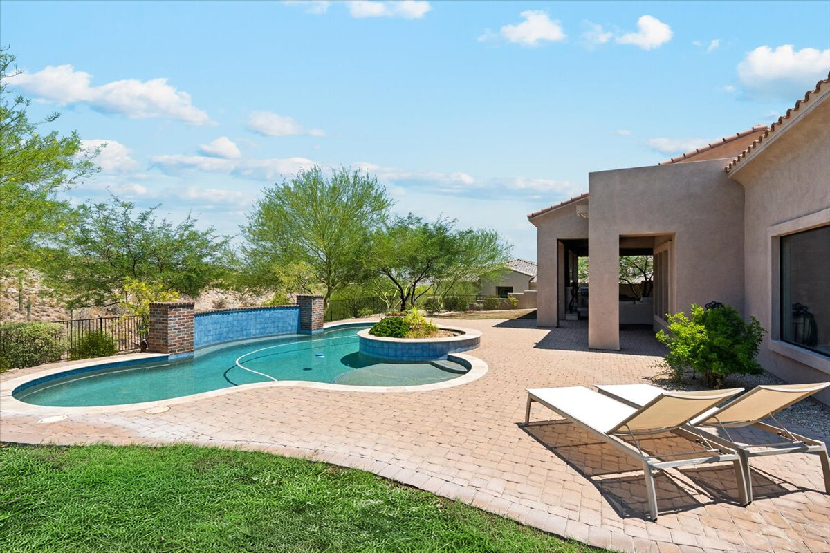 A luxury backyard features a pool, spa, and a covered patio area.