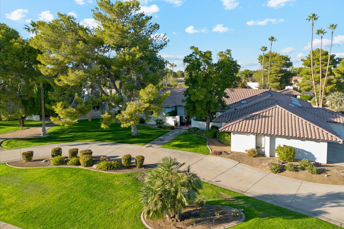 Spacious suburban home with a circular driveway, green lawn, and southwestern-style architecture.