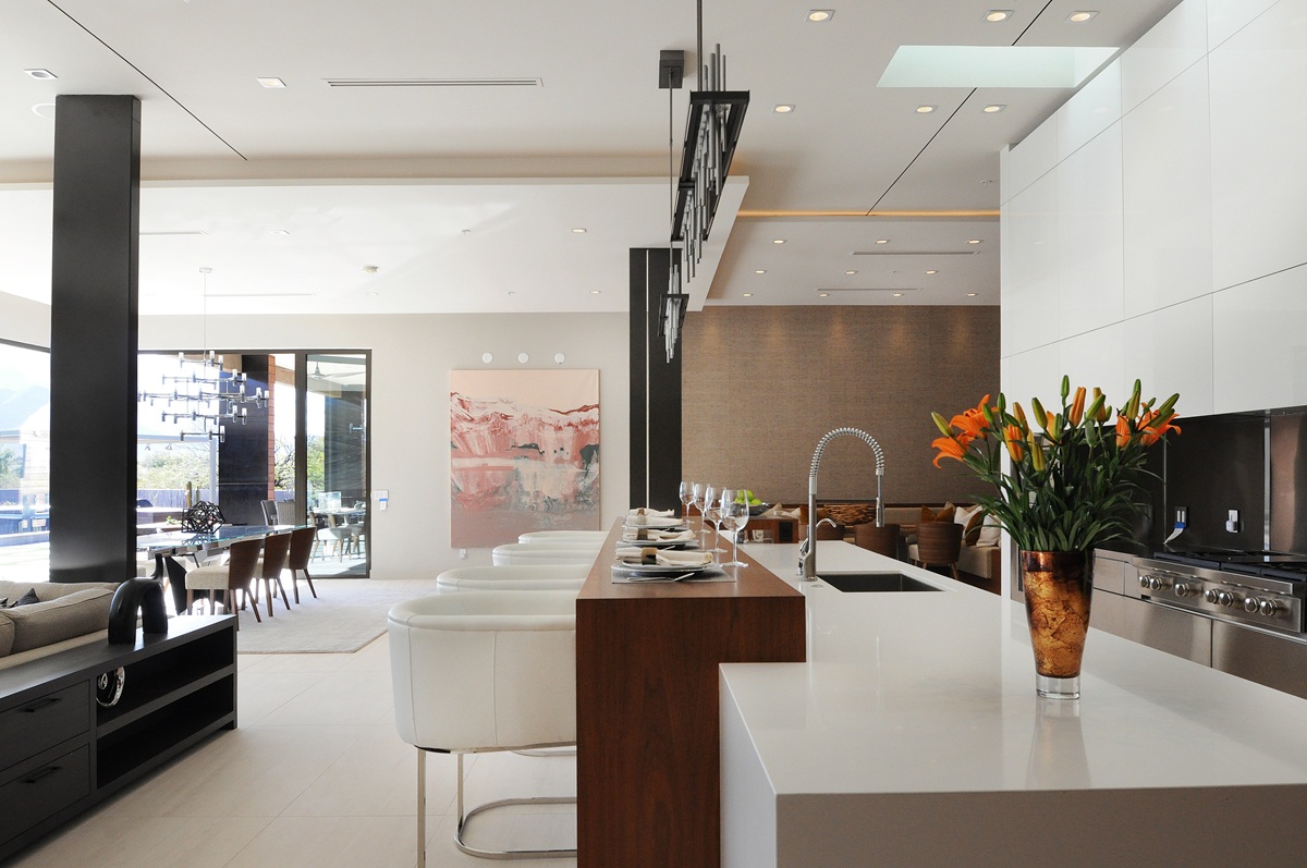 Modern kitchen with white countertops, bar stools, and decor.