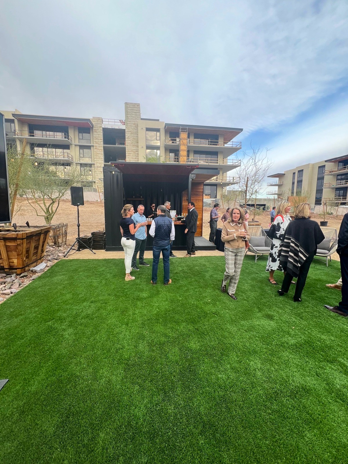 Social gathering with attendees mingling near an outdoor bar setup against a modern Ascent condos backdrop.
