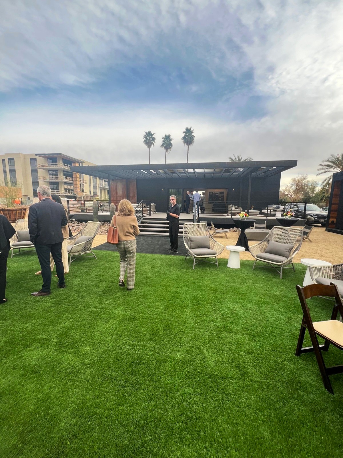 Guests walking toward a modern event pavilion with palm trees and outdoor seating area.