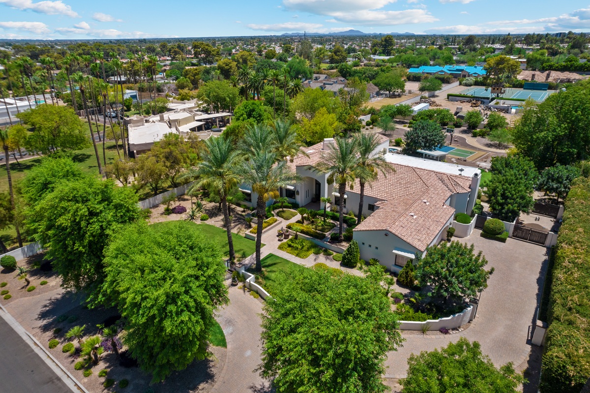 Aerial view of a large home with palm trees and desert landscaping in Arizona.
