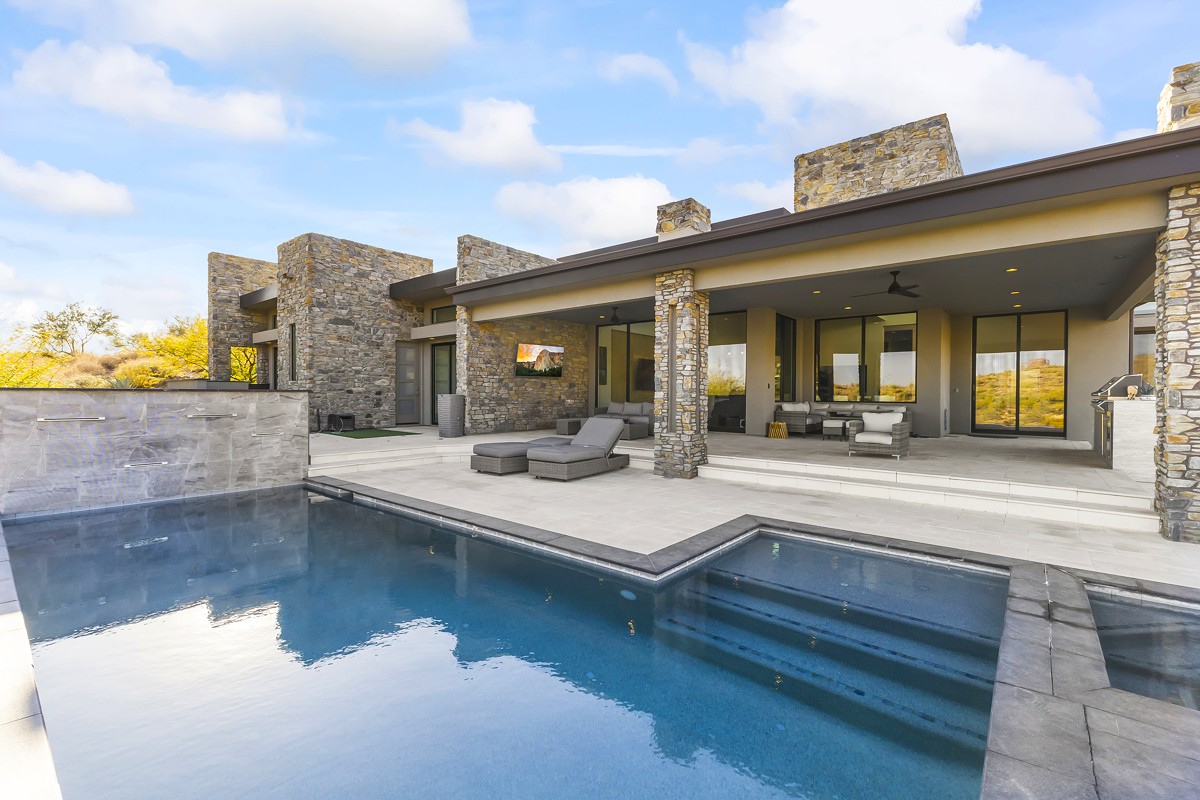 Sleek modern home with a geometric pool, stone accents, and a private patio.