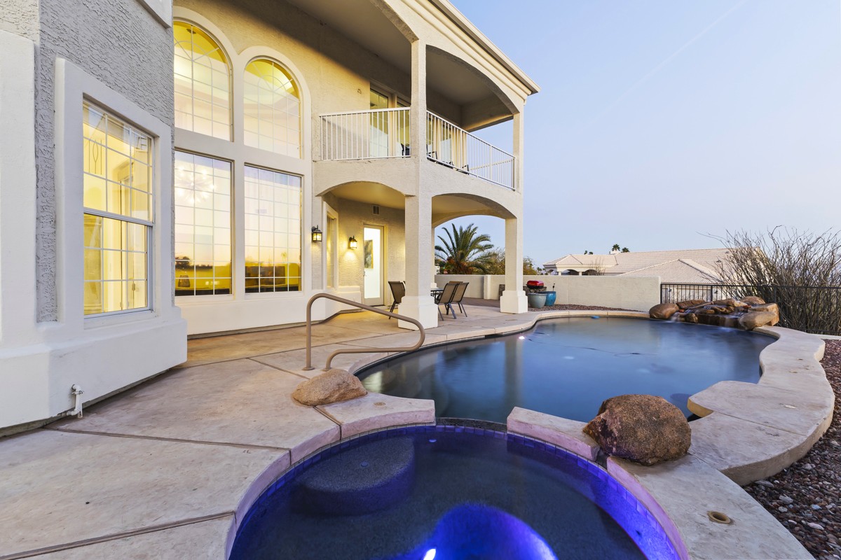 Luxury two-story home with large windows and a pool with a connected spa.