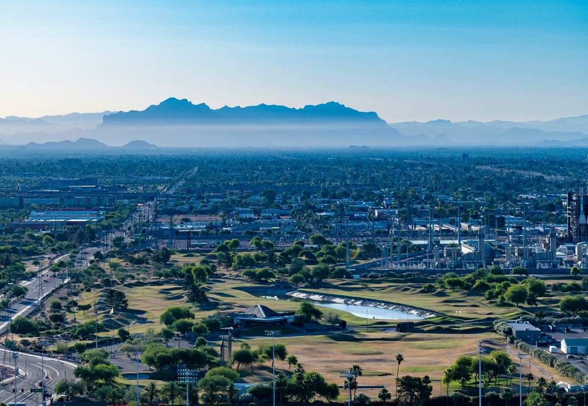 A clear morning view of Greater Phoenix, Arizona, showing suburban sprawl, golf courses, and distant desert mountains.