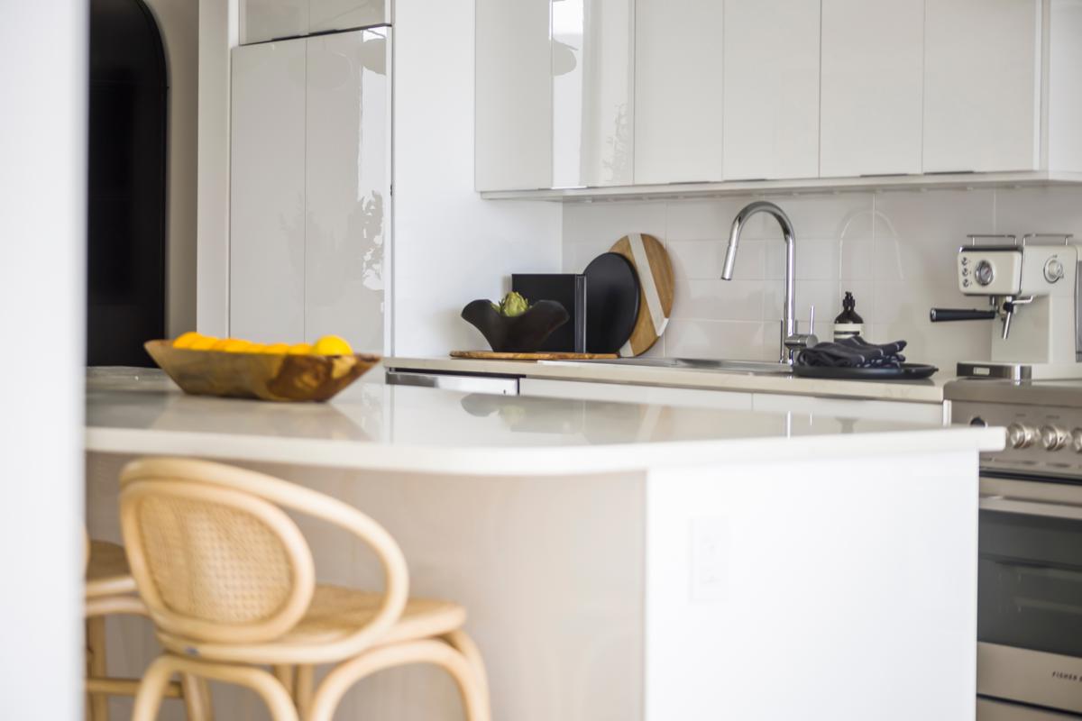 Bright white kitchen with bar seating and modern decor.