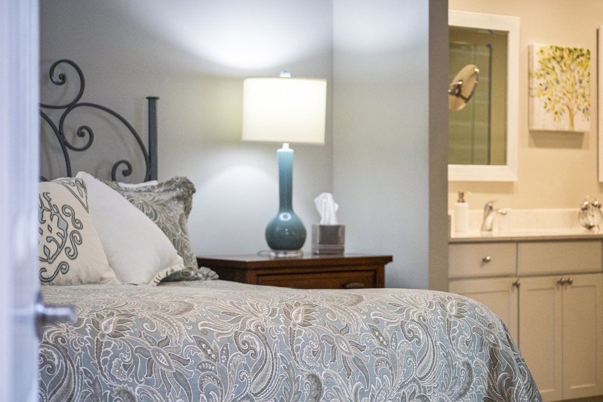 Cozy bedroom with patterned bedding and view into modern bathroom.