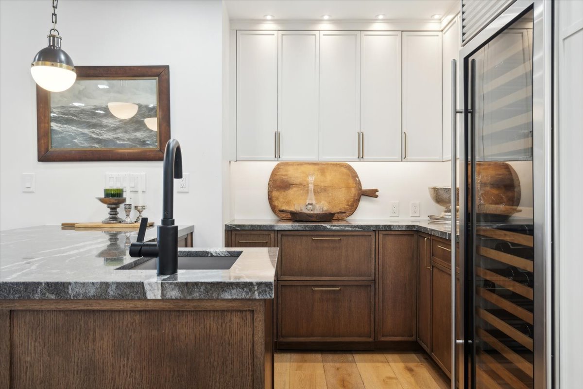Modern kitchen with wood cabinets, marble countertops, and black faucet.