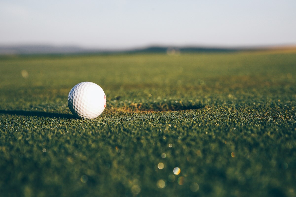 golf ball next to hole in putting green
