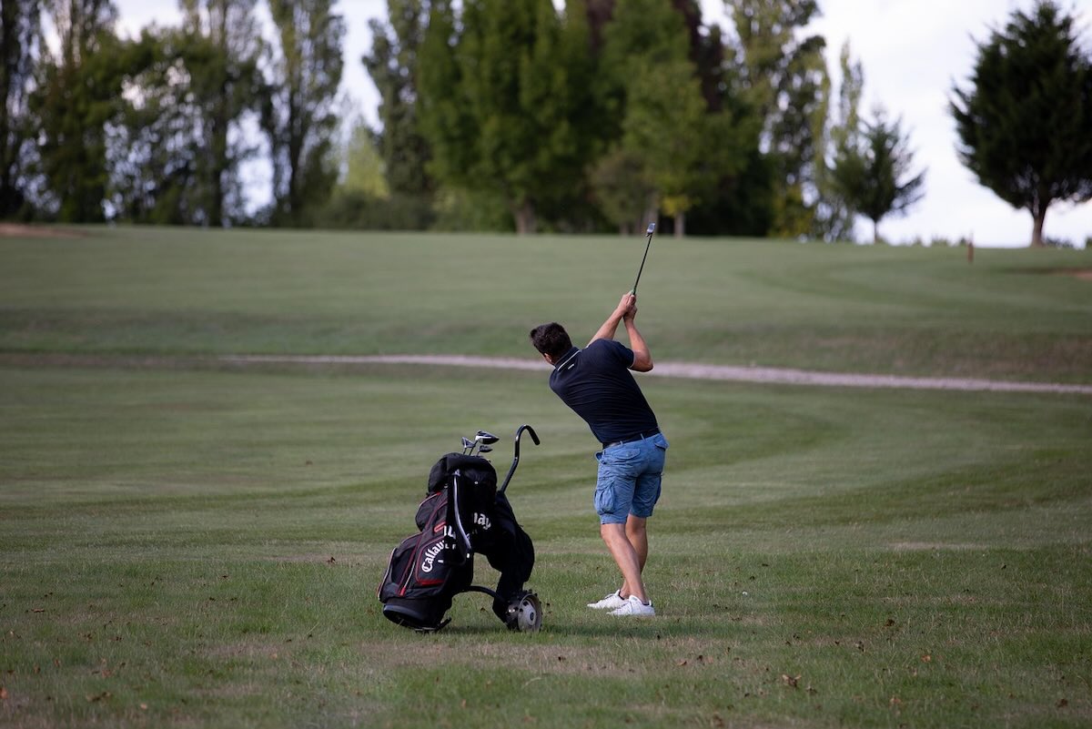 man swinging a pitching wedge on a course