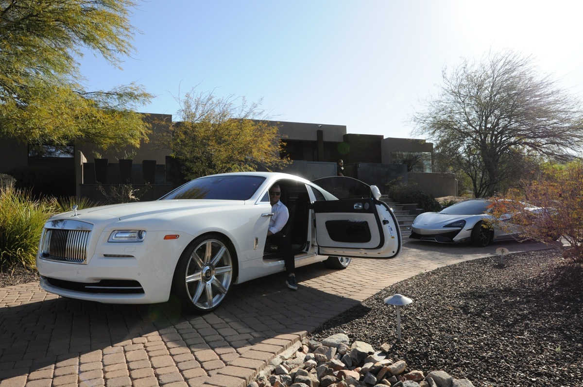 Luxury cars parked outside a contemporary desert home.