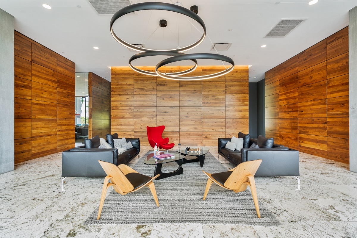 Stylish condo lobby with wood-paneled walls, circular modern light fixtures, and contemporary seating.