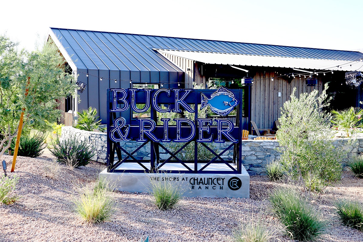 Neon Buck & Rider seafood restaurant sign with fish logo at The Shops at Chauncey Ranch.